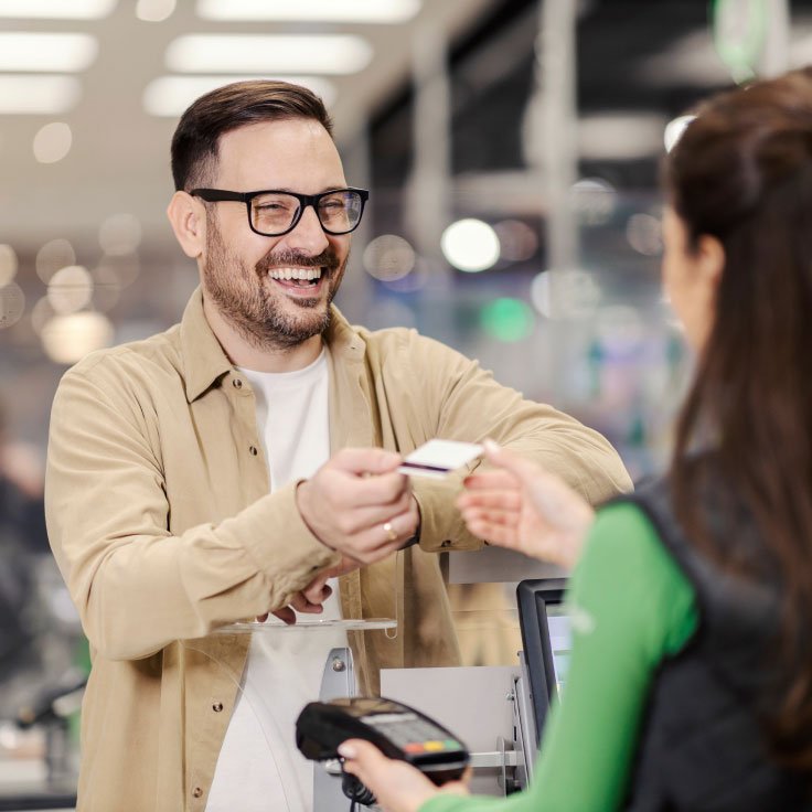 Man hands over his credit card to a store clerk.