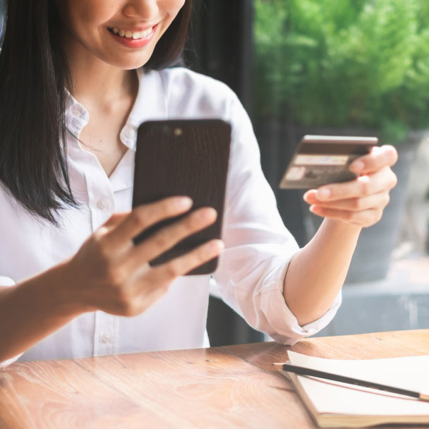 Woman using a credit card to make a purchase via  her mobile phone.