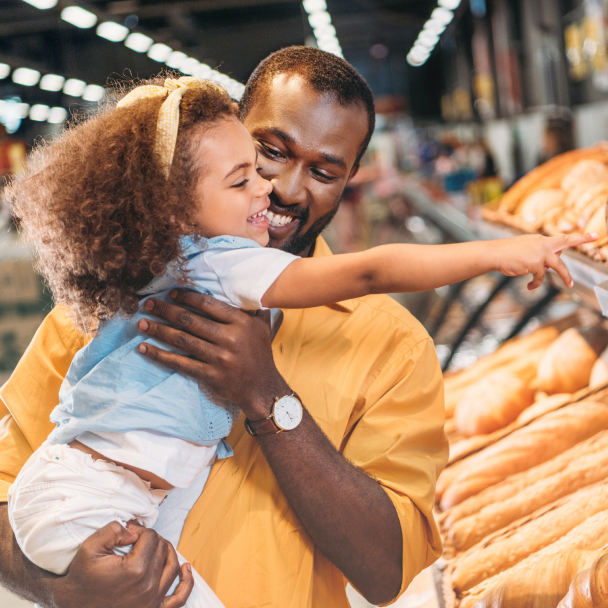 Father and small daughter happily shop in a bakery.