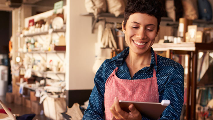 Shopkeeper taking a payment via her tablet.