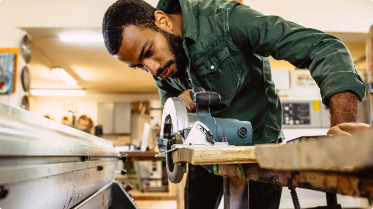 Man works with wood-working tools.